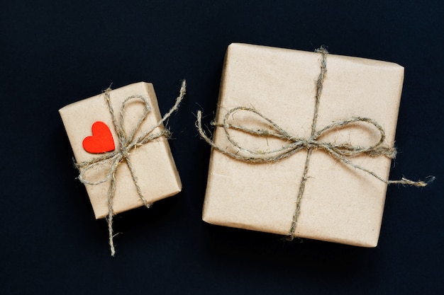 Caixa de presente artesanal embrulhada em papel ofício com coração de madeira vermelho, corda e arco em preto