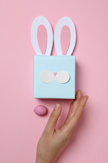 Caixa de presente azul com orelhas de coelho em fundo rosa
