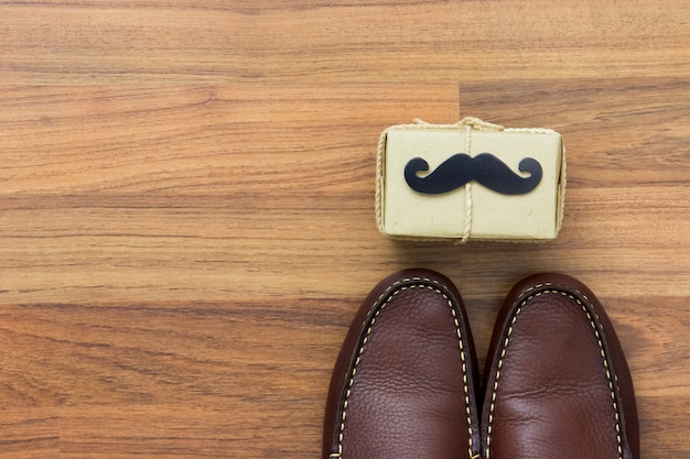 Caixa de presente, bigode de papel, sapatos em fundo de madeira com espaço de cópia. feliz dia dos pais.