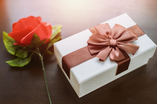 Caixa de presente branca e rosa vermelha na mesa de madeira