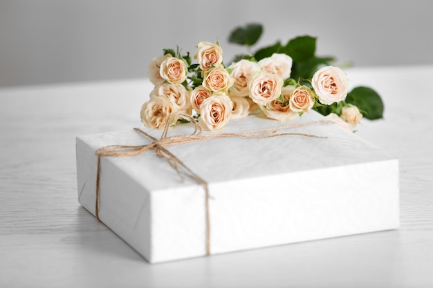 Caixa de presente branca grande com buquê de rosas em cima da mesa