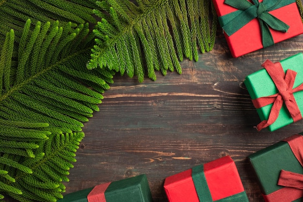 Caixa de presente colorida de Natal com folha de pinheiro e enfeite de decoração na mesa de madeira