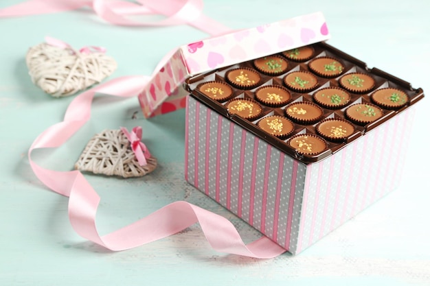 Caixa de presente com saborosos bombons de chocolate na mesa de madeira