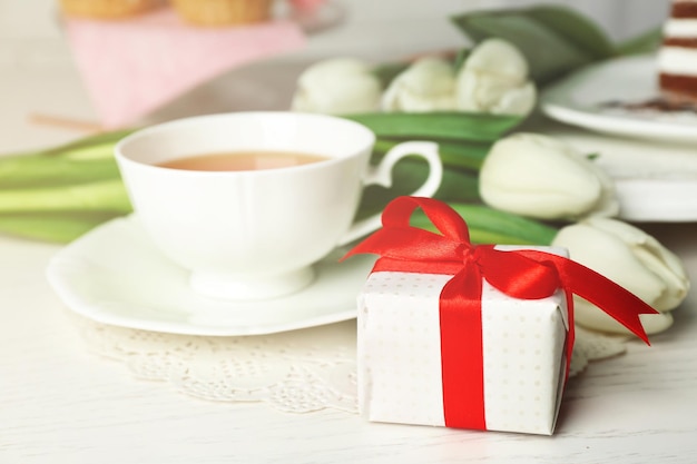 Caixa de presente com tulipas e xícara de chá na mesa de madeira fechada