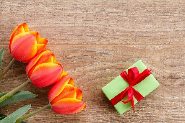 Caixa de presente com tulipas vermelhas em tábuas de madeira. conceito de cartão de saudação. vista do topo.