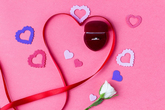 Caixa de presente da fita em forma de coração e uma rosa em um fundo rosa. Presente de Dia dos Namorados