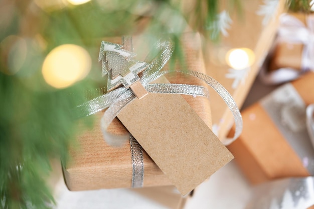 Caixa de presente de feriado Presente de Natal com etiqueta de cartão de endereço sob a árvore de abeto no chão na sala Conceito de Natal