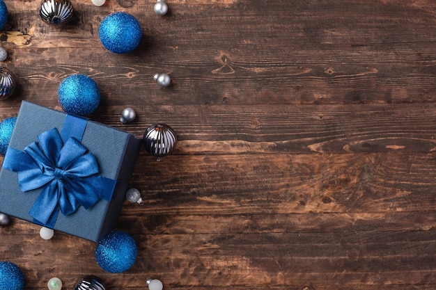 Caixa de presente de Natal azul e enfeite de decoração de bugiganga de prata no fundo da mesa de madeira