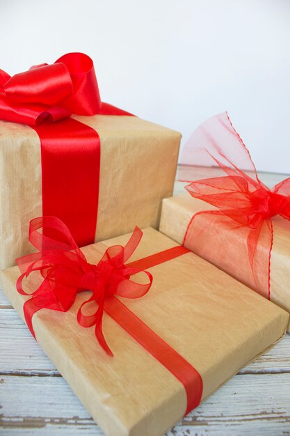 Caixa de presente de Natal com fita vermelha e ramo de abeto no branco sobre pinhas
