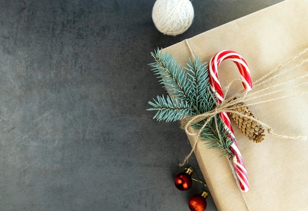 Caixa de presente de Natal com pirulito e galho de árvore de Natal em fundo cinza Lugar para texto