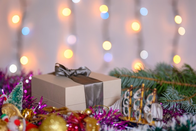 Caixa de presente de Natal decorada com enfeites de Natal no fundo de uma guirlanda cintilante.