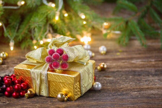 Caixa de presente de natal dourada com luzes na mesa de madeira