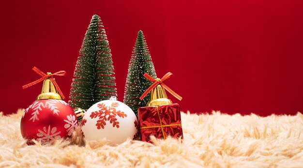 Caixa de presente de Natal e árvore com sinos de ouro, pinhas em fundo vermelho