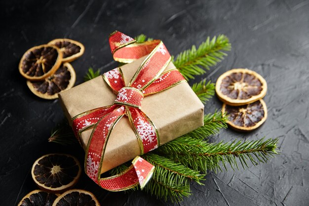 Caixa de presente de Natal e galhos de árvores de abeto gree com frutas secas de laranja em fundo preto