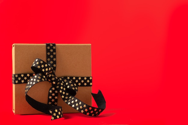 Caixa de presente de natal ou caixa de presente com fita dourada preta sobre fundo vermelho.