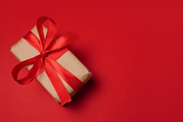 Caixa de presente de papel com laço vermelho sobre fundo vermelho. espaço livre para seu texto.