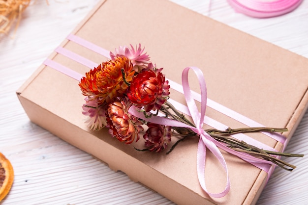 Caixa de presente de papelão decorada com flores secas na mesa de madeira