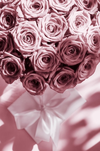 Caixa de presente de seda de férias de luxo e buquê de rosas em fundo rosa blush surpresa romântica e flores como presente de aniversário ou dia dos namorados