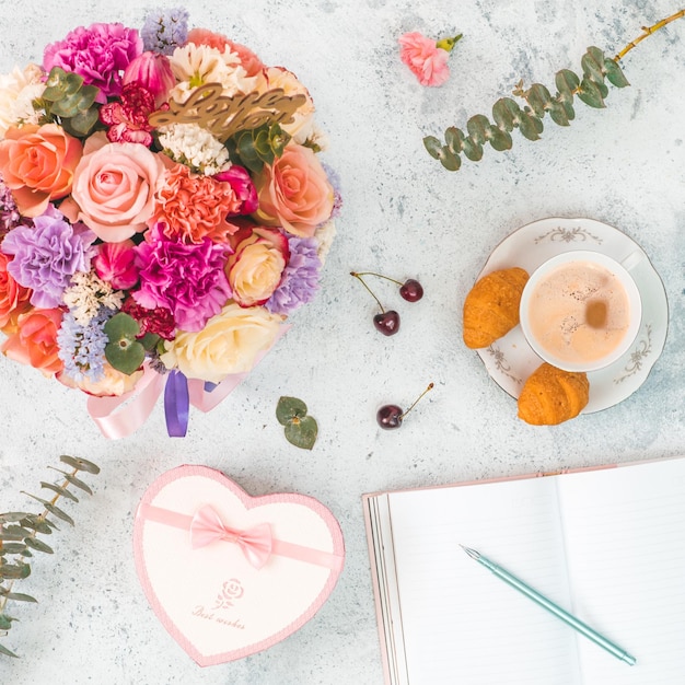 Caixa de presente de xícara de café com um belo bouquet em forma de coração caderno vazio para escrever sonhos e ideias Visão superior formato quadrado Conceito e imagem de ideia para mídias sociais