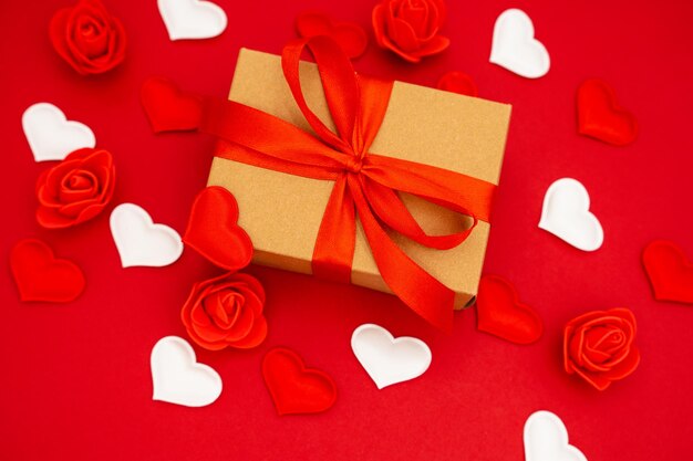 Caixa de presente do Dia dos Namorados de papel kraft com fita vermelha Fundo vermelho com corações e rosas ao redor