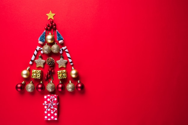 Caixa de presente do Natal, bola vermelha e sino na forma da árvore de Natal, fundo vermelho.