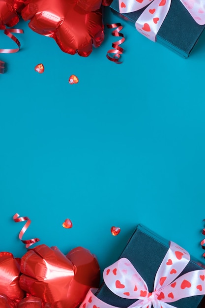 Caixa de presente e balões de forma de coração vermelho em fundo turquesa Cartão de dia dos namorados Copiar espaço