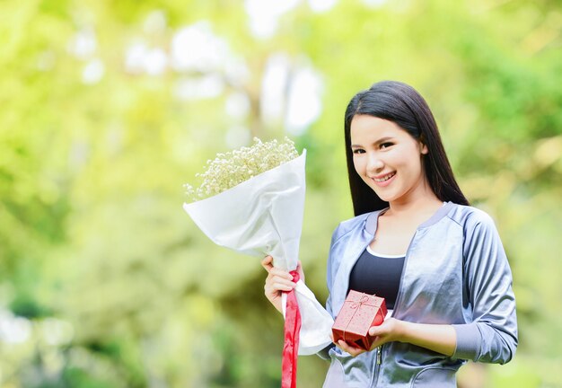 Caixa de presente e buquê de flores na mão mulher Menina asiática linda sorrindo dar um presente para o festival de Natal e ano novo ou dia dos namorados