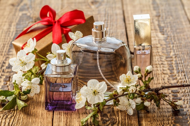 Foto caixa de presente e frascos de perfume com ramo florido de jasmim no fundo de madeira