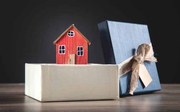 Foto caixa de presente e modelo de casa na mesa de madeira.