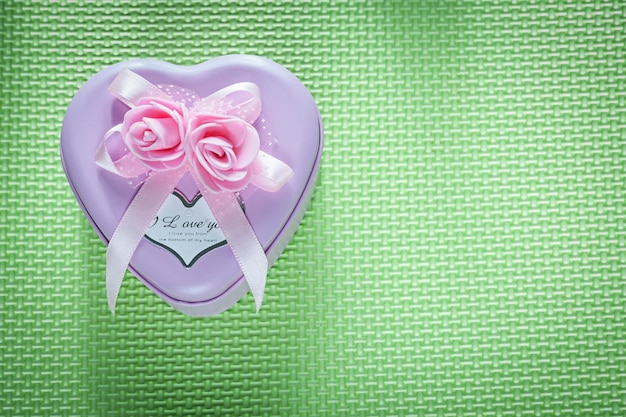 Foto caixa de presente em forma de coração roxo de metal com laço no conceito de celebrações de fundo verde