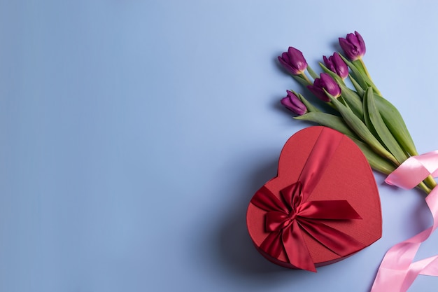 Foto caixa de presente em forma de coração vermelho e buquê de tulipas frescas