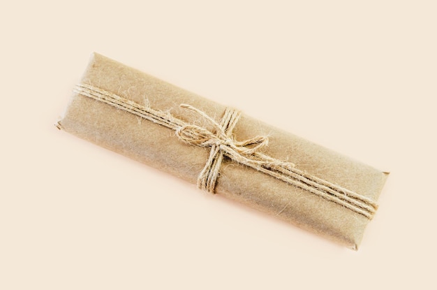 Caixa de presente em papel kraft e amarrada com barbante em fundo bege Caixa vintage feita de ecopaper marrom