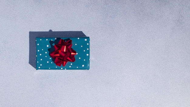 Caixa de presente embrulhada em papel azul aqua com laço vermelho sobre fundo cinza Conceito de cartão de Natal Mockup