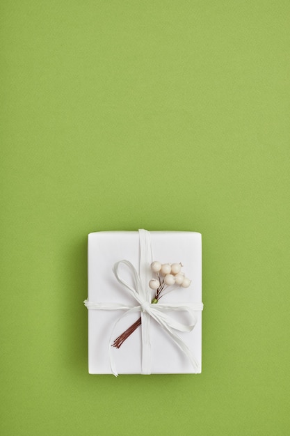 Foto caixa de presente embrulhada em papel branco e decorada com bagas em gr