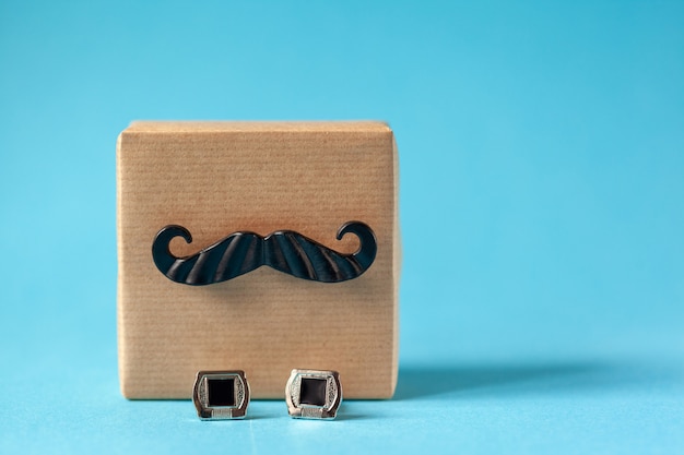 caixa de presente embrulhada em papel ofício com bigode e abotoaduras
