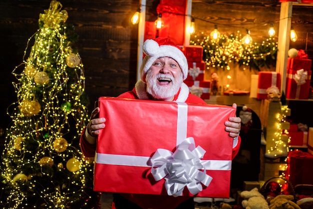 Caixa de presente feliz natal e feliz ano novo véspera de ano novo papai noel dá um presente sorridente homem em