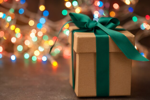 Caixa de presente Kraft no fundo da árvore de Natal e luzes