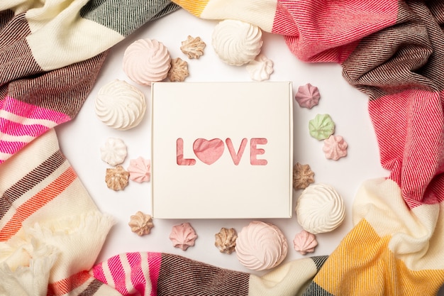Caixa de presente, lindo lenço, merengues e doces em um fundo claro. Composição do Dia dos Namorados. Bandeira. Camada plana, vista superior.