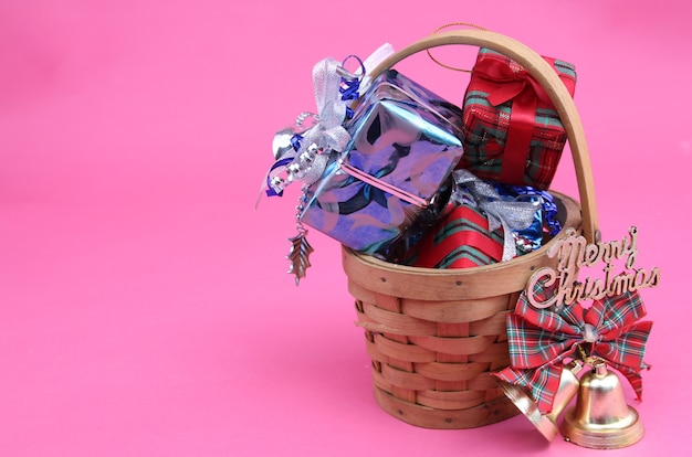 Foto caixa de presente na cesta de dia de natal com fundo rosa.