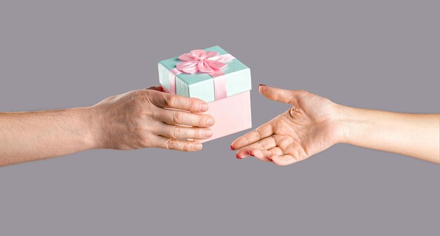 Caixa de presente na mão surpresa e conceito de feriado Mãos de homem segurando um presente de dia dos namorados Mãos masculinas e femininas segurando uma caixa de presentes rosa Menina dá um presente para o homem