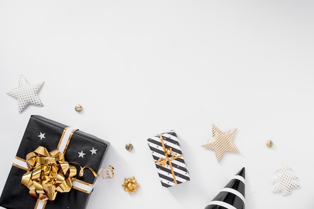 Caixa de presente ou presente, chapéus de festa e estrelas na mesa branca. Composição de Natal com enfeites pretos e dourados