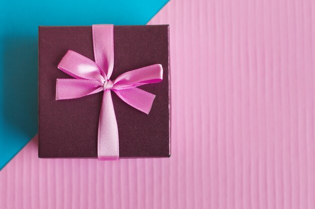 Caixa de presente pequena com fita rosa e laço em um colorido azul e rosa
