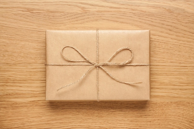 Caixa de presente pequena com laço embrulhado em papel artesanal na mesa de madeira
