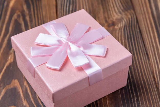 Caixa de presente rosa decorativa com laço na superfície de madeira marrom