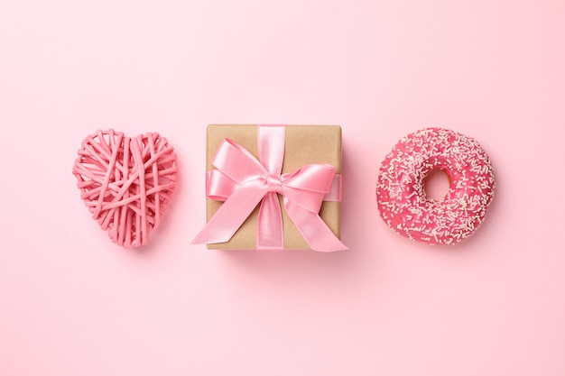 Foto caixa de presente, rosquinha e coração em fundo rosa, espaço para texto