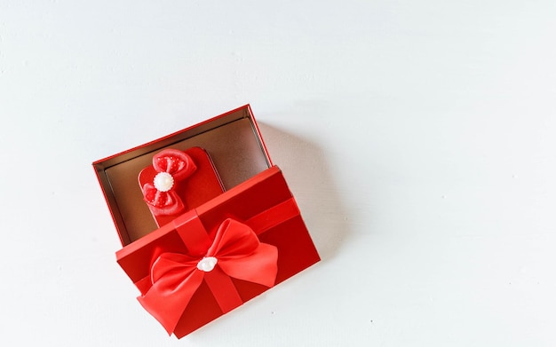 Caixa de presente vermelha aberta na mesa de madeira branca