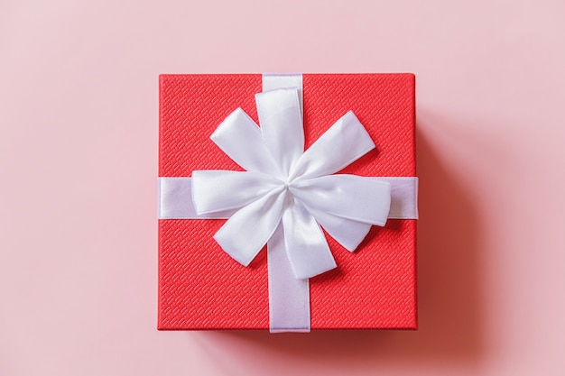 Caixa de presente vermelha de design minimalista isolada em fundo colorido rosa pastel