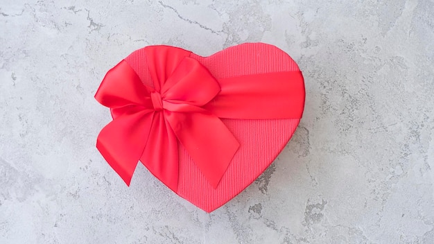 Caixa de presente vermelha em forma de coração em um fundo cinza