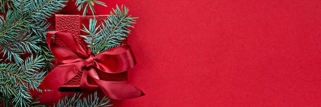 Caixa de presente vermelha festiva com galhos de pinheiro em um fundo vermelho. Férias de conceito de Natal e Ano Novo