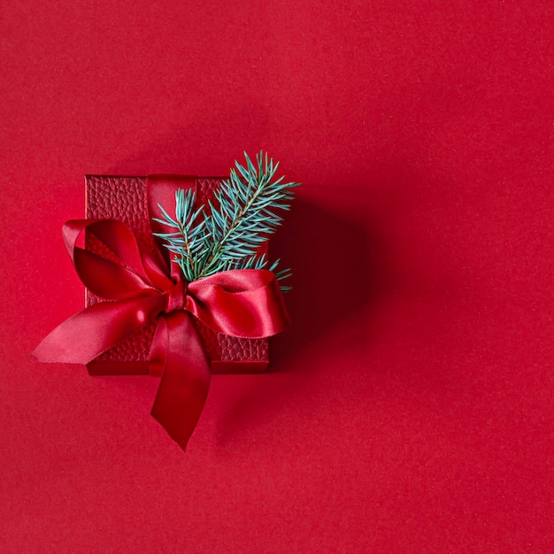 Caixa de presente vermelha festiva com ramos de abeto, sobre um fundo vermelho. Conceito de natal e ano novo, feriado